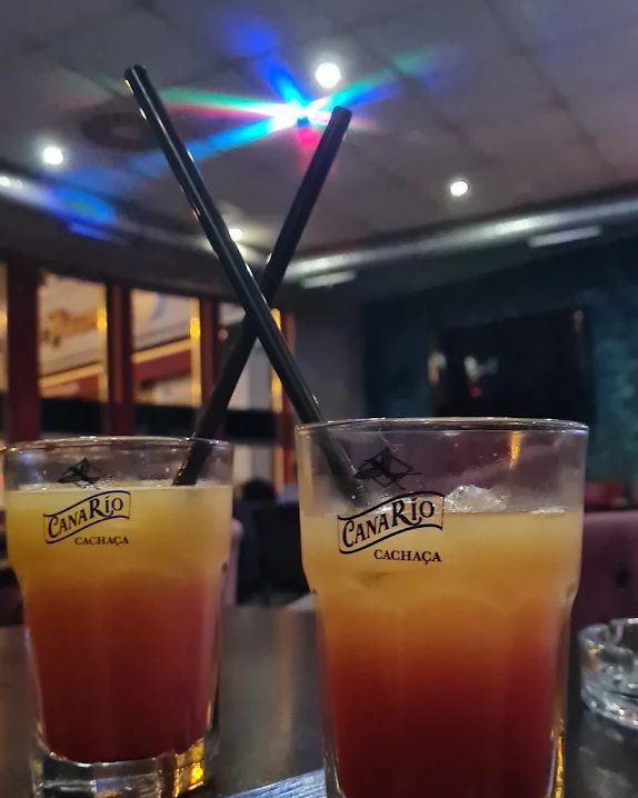 Zwei Longdrinks in Sternzeit-Gläsern auf einem Tisch, darüber die Lichtpunkte einer Discokugel.