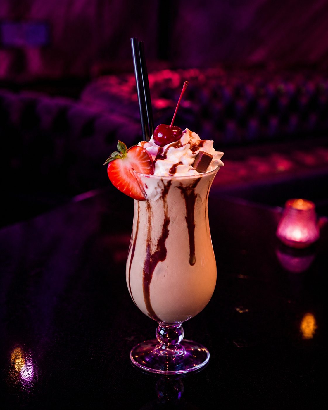 Cremiger Cocktail mit Sahnehaube, Schokosauce, Erdbeere und Kirsche.