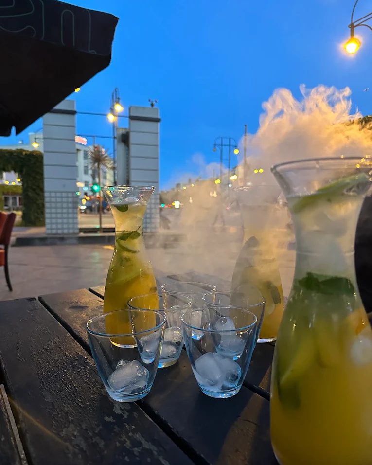 Gelbe und grüne Cocktails mit Nebel im Außenbereich des Sternzeit, im Hintergrund der Abendhimmel.